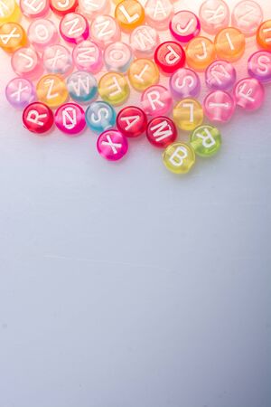 Multi color alphabet letter beads placed randomly on white backgroundの写真素材