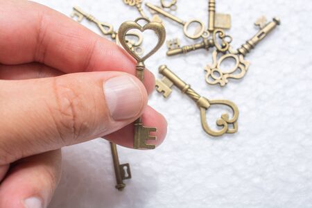 Hand holding a heart shaped key on white background over other keys