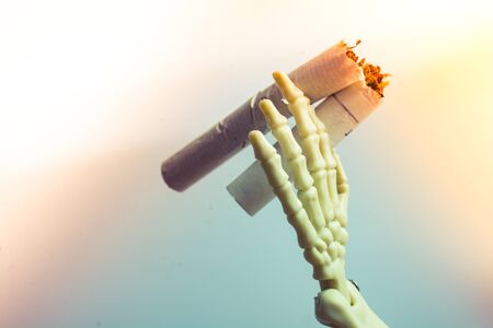 Skeleton figure breaking a cigarette on white background. Smoking kills.