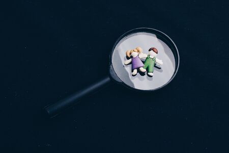 Boy and girl figurine on magnifying glass  as people conceptの写真素材