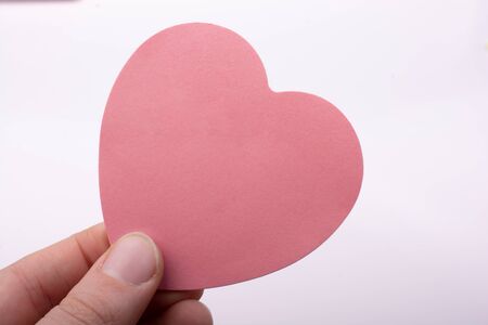 Pink color heart shaped paper in hand as love concept