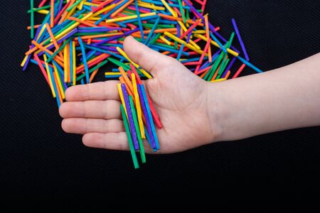 Kid playing with coloured wooden  sticks for creativity on white background