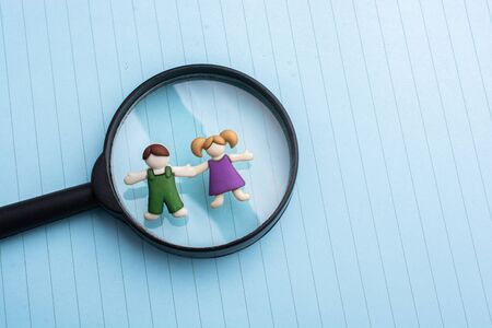 Boy and girl figurine on magnifying glass  as people conceptの写真素材