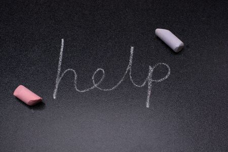 Help word written in chalk on a black chalkboard.