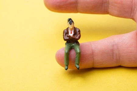 Figurine model men sitting on finger of hand