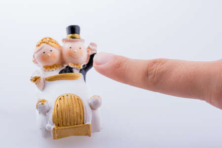 Hand pointing to a newly married husband and wife in a car miniature