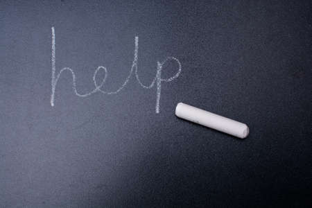 Help word written in chalk on a black chalkboard.
