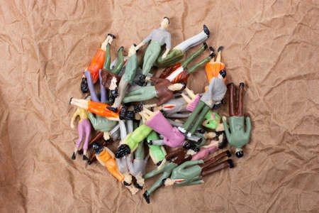 A crowd of miniature people on a brown paper backgroundの写真素材