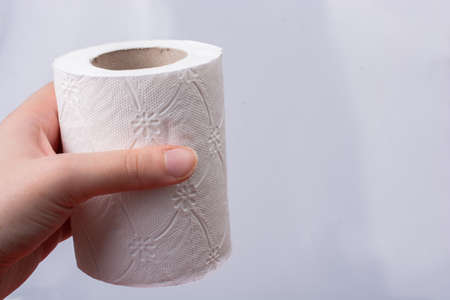 A female hand takes a roll of white toilet paper in hand.の写真素材