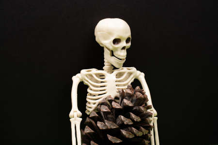 Skeleton hand pressing on man figurine on red .  Death concept