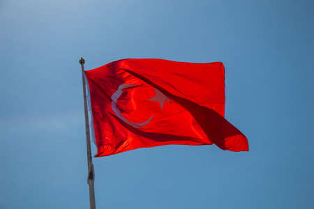 Turkish national flag with white star and moon on a pole in sky