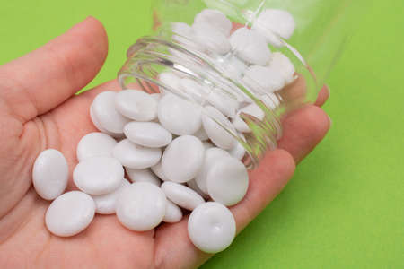 White pill in glass  bottle in hand.  Container Pharmacy.