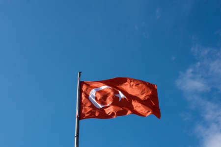 Turkish national flag with white star and moon on a pole in sky