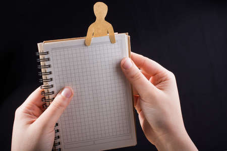Man shape cut out of paper in notebbok in handの写真素材