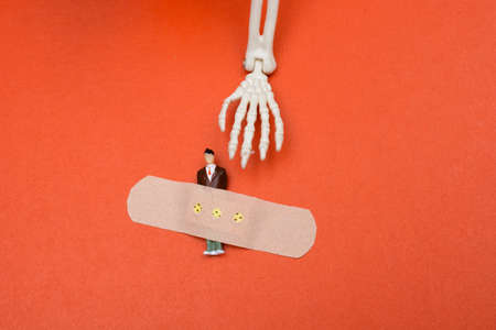Applied  medical sticky plaster to the injured man figurine. Hand of a model skeleton
