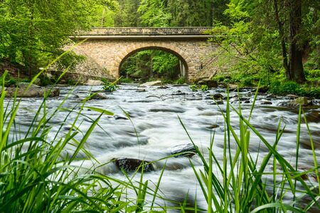 View of the stone bridge Zemská brána and a mountain river in the woodsの写真素材