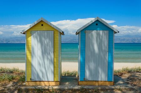 Yellow and blue public changing room on the seafront, view of the blue water.の写真素材
