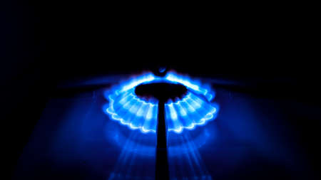 Blue flame from a burner in a gas stove on. Illuminated flame on a dark background, photo taken at...