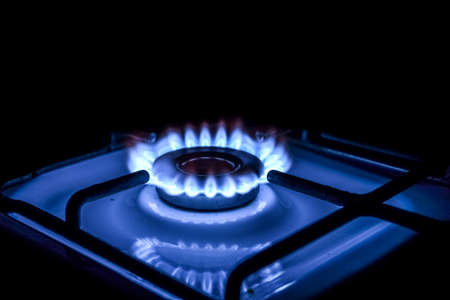 Blue flame from a burner in a gas stove on. Illuminated flame on a dark background, photo taken at...