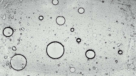 Round fat bubbles float on the water surface. Top view of circles of different sizes.