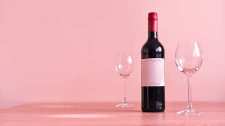 A bottle of red wine with two empty glasses. A wine set for two stands on the table, preparing for...