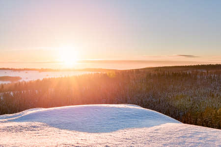 Sunset over the forest, winter view from the lookout point in the Stolowe Mountains. The mountain valley is illuminated by the rays of the setting sun.の写真素材