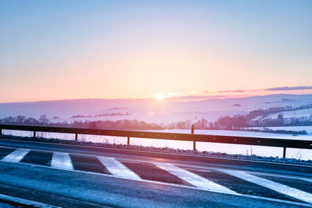 Winter landscape, sunset over the hills near the national road. View of the snow-covered fields lit by the rays of the sun.の写真素材