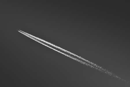 A passenger plane flies at high altitude and leaves a condensation trail behind it. Condensed water vapor creates a characteristic trail in the sky behind a jet plane.の写真素材