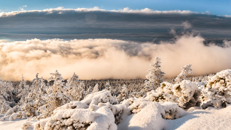 Winter landscape in the Polish mountains of the Sudetes, low clouds in the valley illuminated by the...