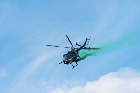 Leszno, Poland - June, 17, 2022: Antidotum Airshow Leszno, Bolkov Bo-105 light twin-engine multi-role helicopter. The helicopter pilot flies down leaving green smoke behind the plane.のeditorial素材