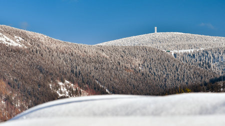 Winter landscape in the Polish mountains of the Sudetes, a view of the snow-capped mountain peaks, an observation tower on the top of Snieznik.の写真素材