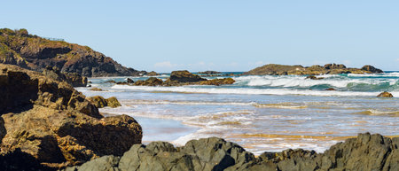 Australian coast with volcanic rocks at the shore, view from the beach to the horizon with blue water with waves on a summer sunny day.の写真素材