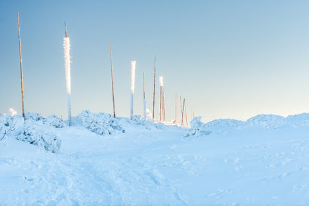 Hruby Jesenik, Snow-covered mountain hiking trail leads to the top of the mountain, tall poles mark...
