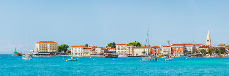 The coastal town of Porec in Croatia with many boats floating in the bay, seen from the seaside promenade on a sunny day.の写真素材