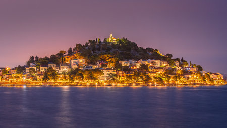 Nighttime panorama of the town of Tribunj in Croatia, featuring a seafront, illuminated promenade,...