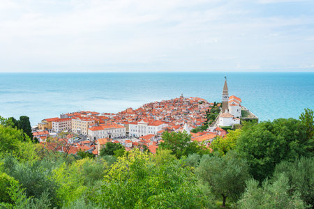 The coastal town of Piran in Slovenia, a picturesque seaside landscape, seen from the Walls of Piran tourist attraction. Colorful buildings surrounded by blue water.の写真素材