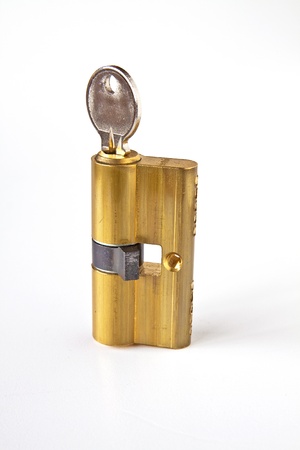 Brass cartridge cylinder with key on a white backgroundの写真素材