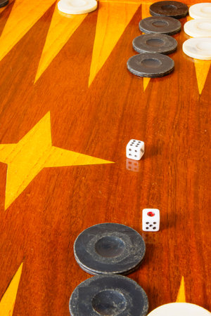 Old varnished wooden board game with plastic checkers and dice. Selective focus with shallow depth...