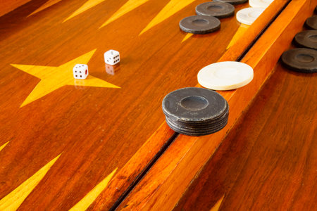 Old varnished wooden board game with plastic checkers and dice. Selective focus with shallow depth...