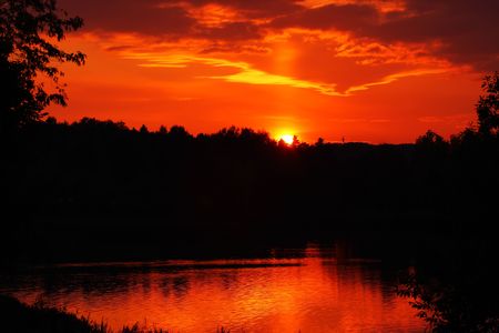 Red sunset in the lake. Dark forest.の写真素材