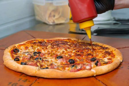 The finished pizza is poured with ketchup.の写真素材