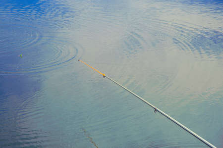 Fishing rod over the water, waiting for the bite.の写真素材