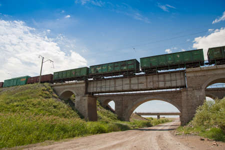 An old railway bridge, a freight train is crossing it.の写真素材
