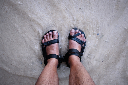 Feet on sandal against the wite sand.の写真素材