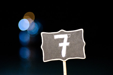 Number seven on a black background with bokeh light.の写真素材