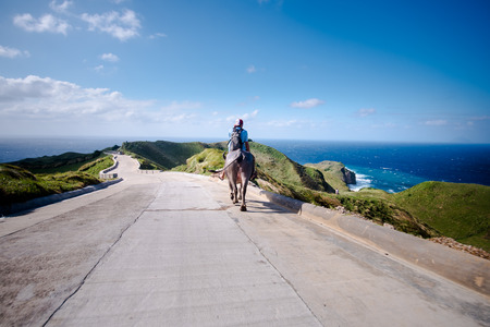 Farmer riding his Carabao at the hills of Batanes, Philippines.の写真素材