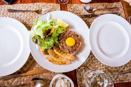 Steak Tartare with fresh organic vegetables serve on local table setting.