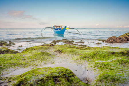 Blue fishing boat at the shore under the clear blue sky.の写真素材