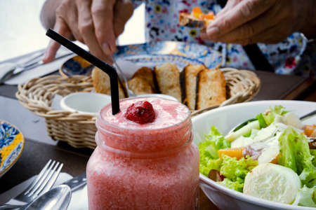 Strawberry shake, vegetable salad and bread on the table.の写真素材