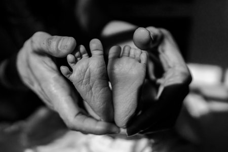 Close up photo to an infant baby's feet held in adult's hand.の写真素材